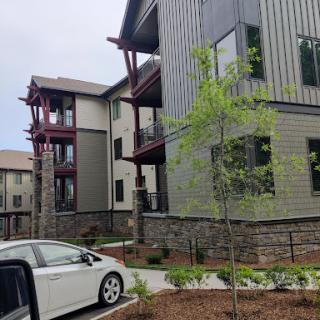 A modern apartment building with a landscaped entrance and a parked vehicle.