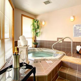 A luxurious indoor spa room featuring a hot tub, champagne, and a serene atmosphere.
