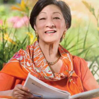 A woman smiling and holding a book outdoors.