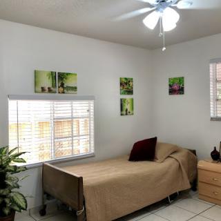 A cozy, minimalist bedroom featuring a single bed, natural light from the window, and decorative wall art.