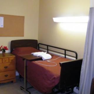 A hospital room featuring a single bed with medical equipment and a bedside table.
