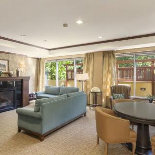 A cozy living room featuring a fireplace, comfortable seating, and large windows with curtains.