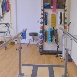 A physical therapy room featuring parallel bars and various exercise tools for rehabilitation.