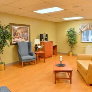 A cozy living room with seating, tables, and decorative plants.