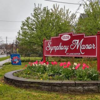 A sign for Symphony Manor surrounded by a flower bed of tulips.