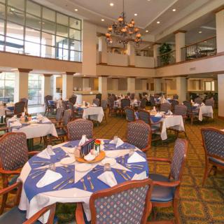 An elegantly set dining area with multiple tables, chairs, and a chandelier.