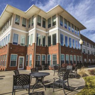 Modern building with outdoor seating and a bright blue sky.