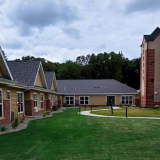 A view of a residential building complex with a neatly maintained lawn under a cloudy sky.