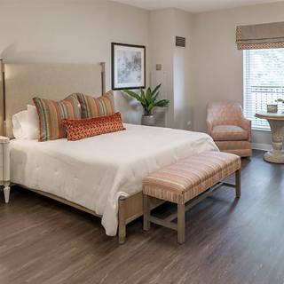 A modern bedroom with a neatly made bed, stylish armchair, and soft lighting.