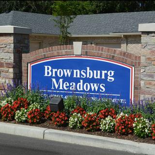 Entrance sign for Brownsburg Meadows surrounded by colorful flowers and brickwork.