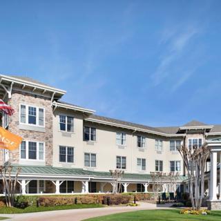 A large residential building with a well-maintained lawn and clear blue sky overhead.