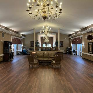 An elegant lobby featuring a stylish chandelier and comfortable seating, highlighted by a spacious wooden floor.
