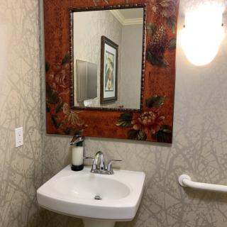 A small bathroom with a decorative mirror, sink, and light fixture.