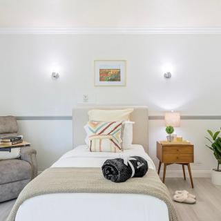 A cozy and minimalist bedroom featuring a neatly made bed, modern lighting, and simple decor elements.