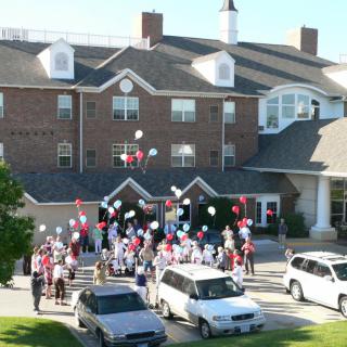 A large group of people celebrating with balloons outside a building.