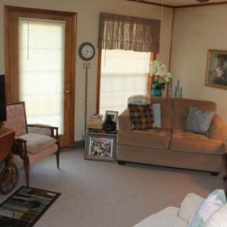 A cozy living room with traditional furnishings, featuring a sofa, armchair, and decorative elements.