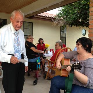 A group of people enjoying an outdoor gathering, with one person playing the guitar and others engaging in conversation.