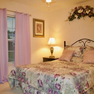 A cozy bedroom with floral bedding and soft lighting.