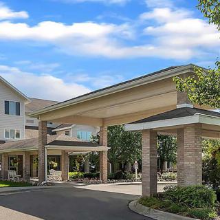 A scenic view of a large building's entrance with a covered driveway and surrounding greenery.
