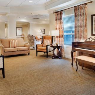 A cozy living room with elegant furniture and a piano by the window.