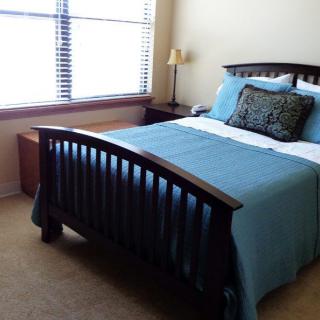 A cozy bedroom with a neatly made bed and a window allowing natural light.