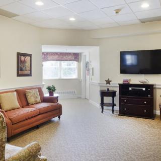 A cozy living room with a sofa, armchair, and a wall-mounted television.