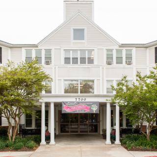 The entrance of a white building with columns and surrounding trees.