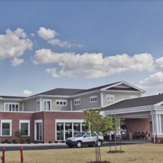 A residential building with a parking lot and car under a partly cloudy sky.