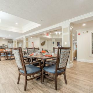 A modern dining area featuring wooden furniture and a neatly set table, illuminated by bright lighting.