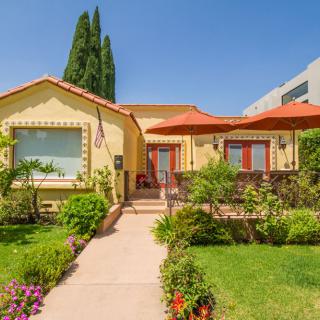 A charming single-story house with a well-maintained garden and vibrant greenery.