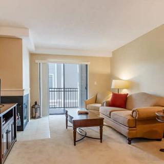 A cozy living room with a sofa, coffee table, and TV, leading to a balcony.