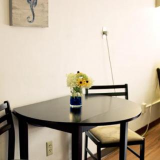 A minimalist dining area with a small round table, two chairs, and a flower vase.