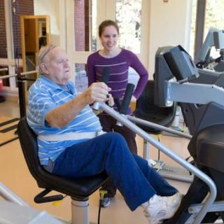 A senior man engaging in a workout with the assistance of a personal trainer.