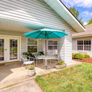 A cozy patio with a table, chairs, and an umbrella, set in the backyard of a house.