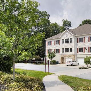 A suburban house with a driveway, surrounded by trees and an overcast sky.