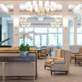 A spacious and elegantly designed lobby with comfortable seating, chandeliers, and a piano.