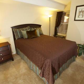 A cozy bedroom with a neatly made bed, nightstand, and floor lamp.