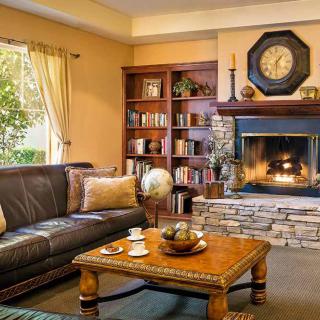 A cozy living room with a fireplace, leather sofa, and a wooden coffee table.