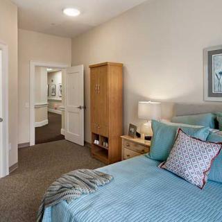 A cozy bedroom with a neatly made bed, wooden wardrobe, and decorative elements.
