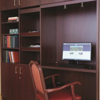 A compact home office setup with a computer desk, bookshelf, and chair.
