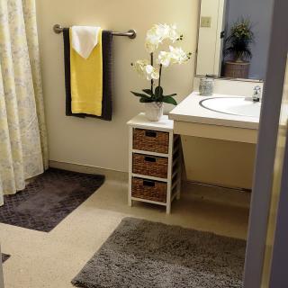A neatly organized bathroom with a yellow towel, plants, and decorative elements.