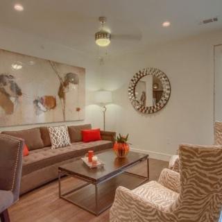 A modern living room with stylish decor, featuring a large sofa, artwork on the wall, and a circular mirror.