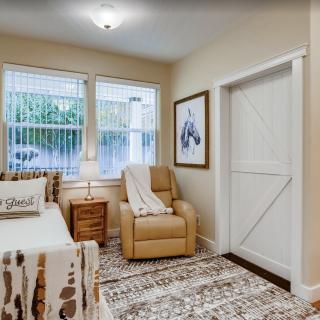 A cozy bedroom interior with a bed, armchair, and decorative rug.