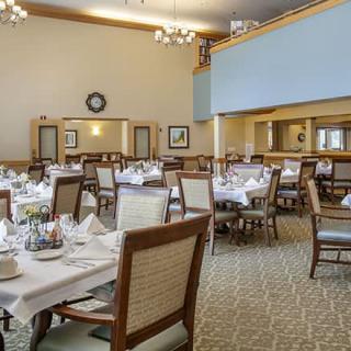 An elegant dining room with neatly arranged tables and chairs, set for a formal meal.