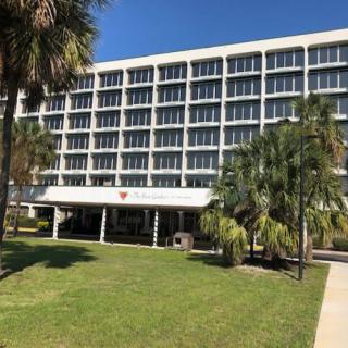 A modern building with palm trees and a well-maintained lawn on a sunny day.