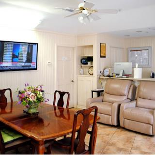 A cozy living space featuring a dining table with chairs, recliners, and a wall-mounted television.