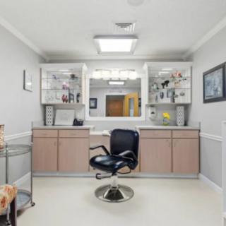 A modern hair salon interior with a styling chair and mirrored shelves.