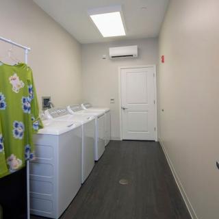 A small laundry room with several washing machines lined up against the wall.