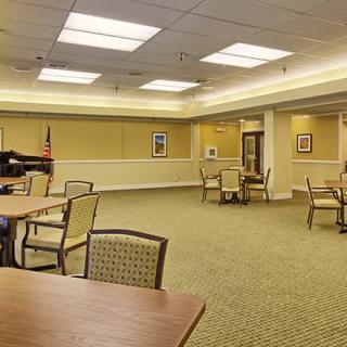An empty conference room with tables and chairs, well-lit and carpeted.