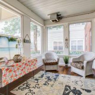 A cozy sunroom with comfortable seating and a decorative rug.